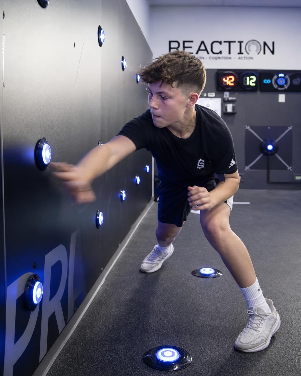 Teenage athlete tapping illuminated reaction training pods during a drill